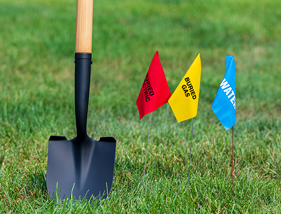 Shovel in grass with 3 locator flags